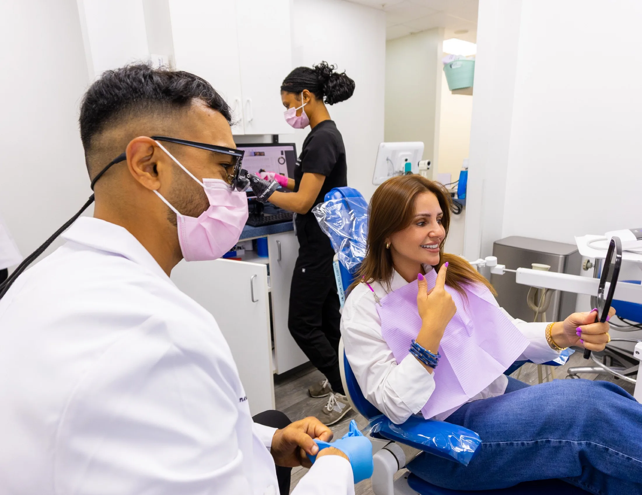 A patient admiring her smile in a mirror at Advanced Dental Care of Fredericksburg