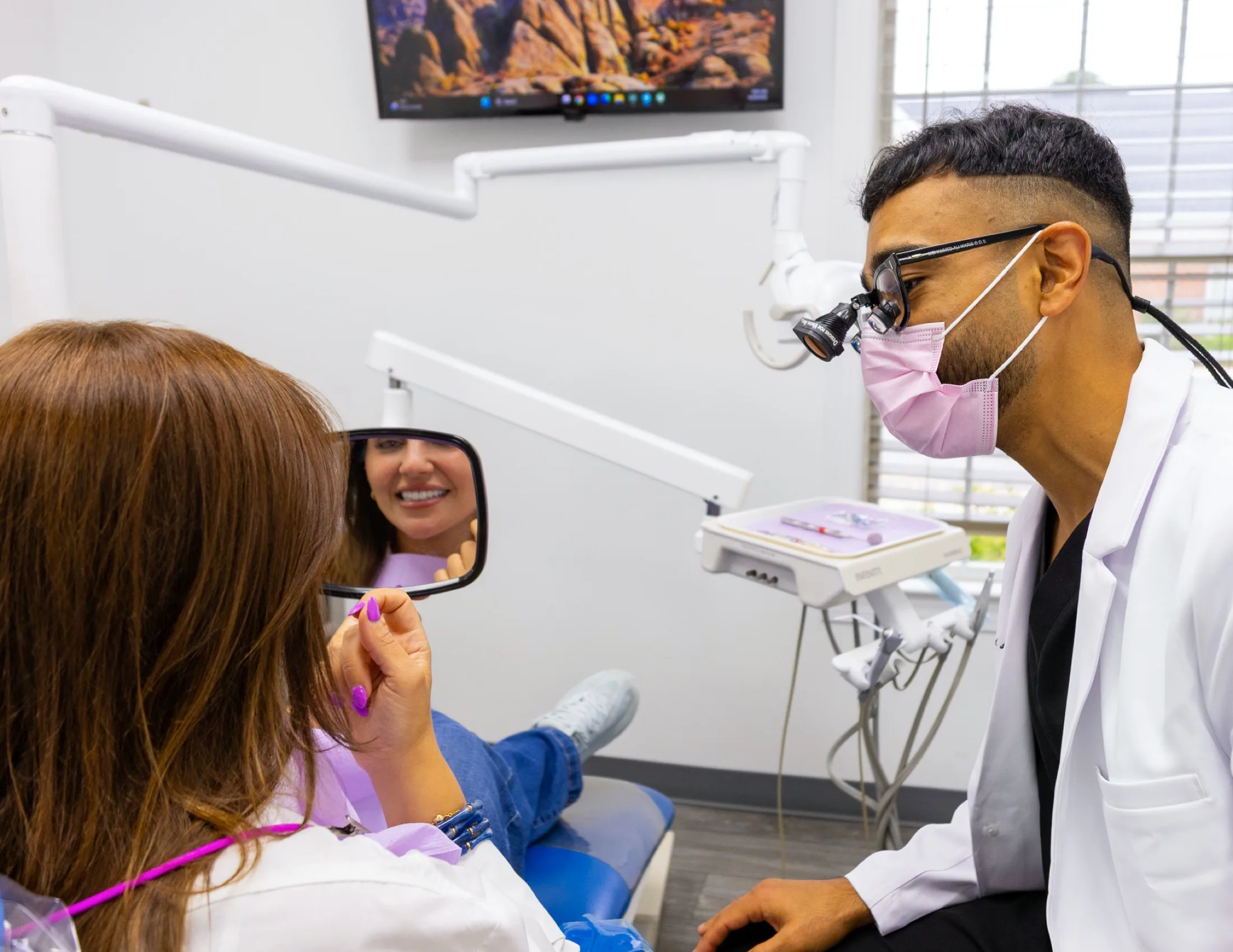 A patient admiring her smile in a mirror at Advanced Dental Care of Fredericksburg